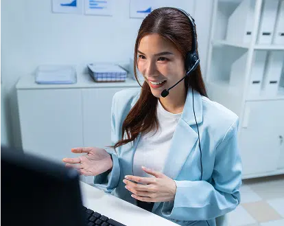 A female support agent talking on a headset looking at a computer