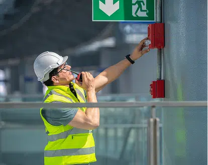 a worker reviewing a fire alarm outside a building