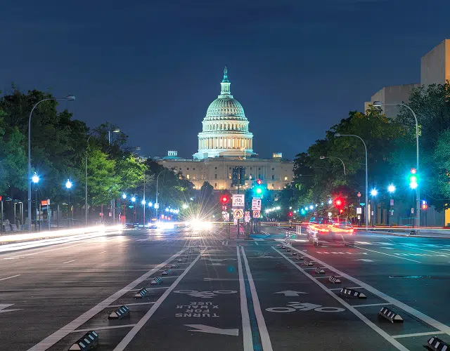 A night view from a road looking toward a government building.