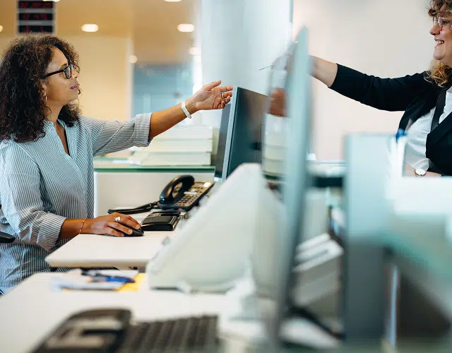 Two woman passing something over a desk